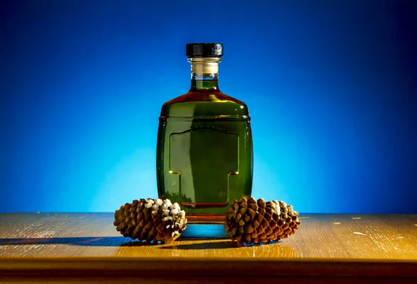 Cognac bottle and pine cones shot on blue background