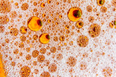 Sıvının yüzeyinde çok renkli köpük kabarcıkları var. Soyut makro resim.