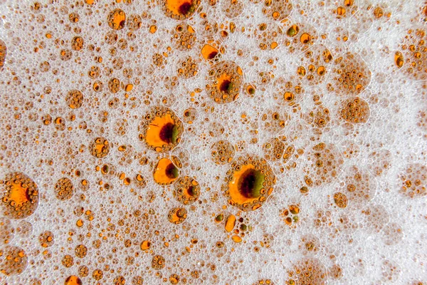 Sıvının yüzeyinde çok renkli köpük kabarcıkları var. Soyut makro resim.