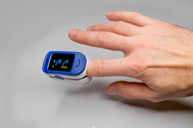 Bir adamın parmağındaki nabız oksimetresi kandaki oksijen miktarını ve nabzını ölçer..