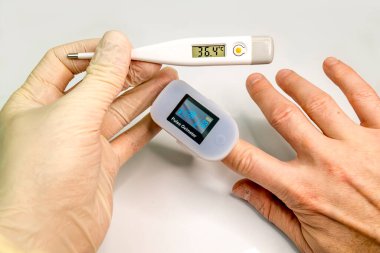 Bir adamın parmağındaki nabız oksimetresi kandaki oksijen miktarını ve nabzını ölçer..