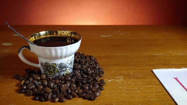 Filiżanka z kawą wśród ziaren kawy i liść z napisem Kocham cię — Wideo stockowe