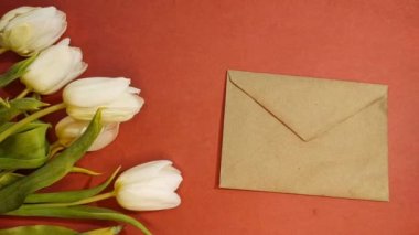 Bir buket güzel lale ve turuncu arka plan manzaralı para dolu bir zarf. Anneler Günü 'nün arka planı, Uluslararası Kadınlar Günü. Holiday, bir hediye ver. 4K görüntülerini durdur..