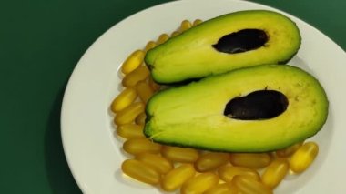 Bir tabakta avokado kamaları ve omega-3 kapsülleri. 