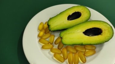 Bir tabakta avokado kamaları ve omega-3 kapsülleri. 