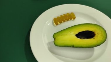Bir tabakta avokado kamaları ve omega-3 kapsülleri. 