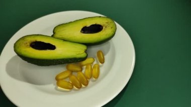 Bir tabakta avokado kamaları ve omega-3 kapsülleri. 
