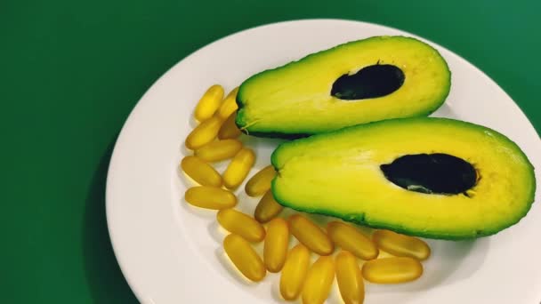 Клинья авокадо и омега-3 капсулы на тарелке. — стоковое видео