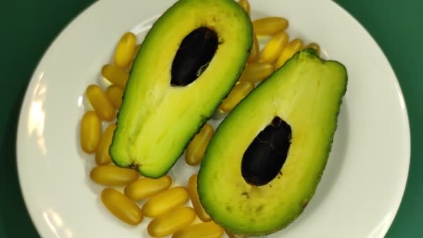 Cuñas de aguacate y cápsulas omega-3 en un plato. — Vídeo de stock