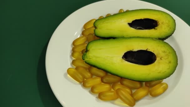 Bir tabakta avokado kamaları ve omega-3 kapsülleri. — Stok video