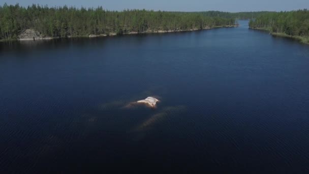 En flicka som solar på en stenö mitt i en sjö i Karelen, Ryssland. — Stockvideo