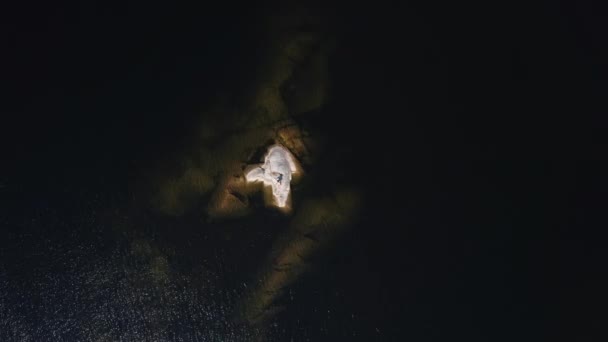 Uma menina toma banho de sol em uma ilha de pedra no meio de um lago na Carélia, Rússia. — Vídeo de Stock