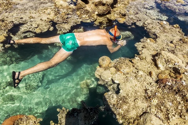 Человек в маске плавает на коралловом рифе в море — стоковое фото