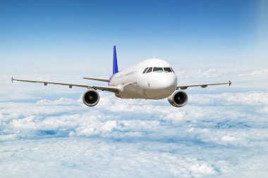 Gökyüzündeki bulutların üzerinde uçan bir yolcu uçağı