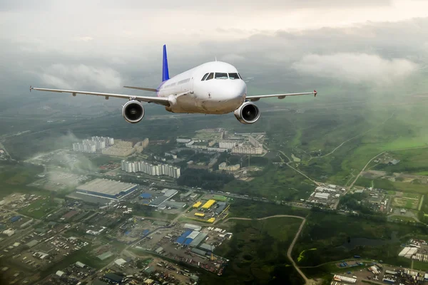 Passagier passagiersvliegtuig trok over de daken van de stad — Stockfoto