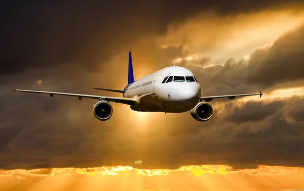 Um avião de passageiros voando no céu ao pôr do sol — Fotografia de Stock