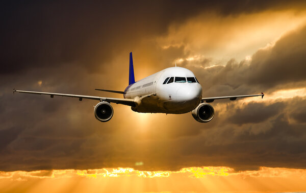 A passenger plane flying in the sky at sunset