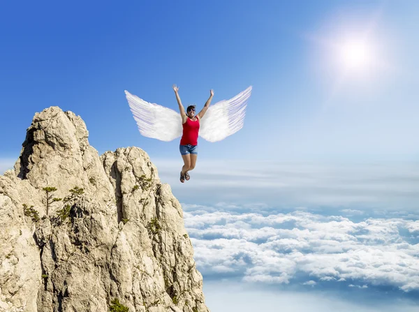 Girl flies on the wings against the background of clouds and mou — Stock Photo, Image