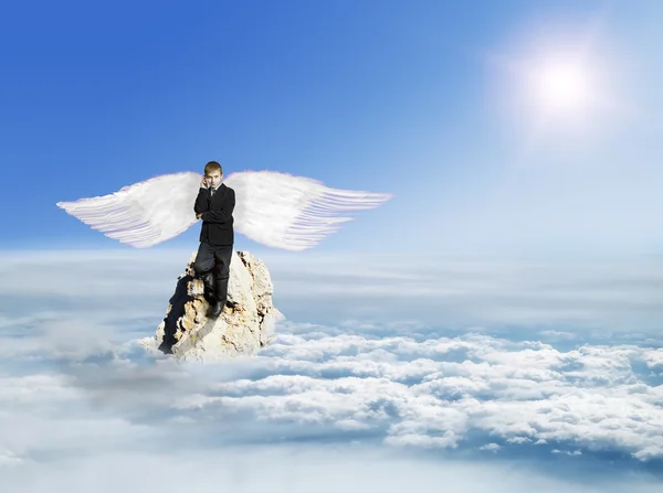 The boy with the phone in the costume with Angel Wings on a rock