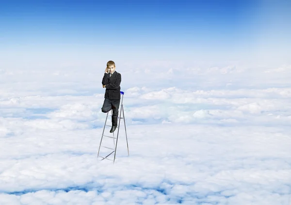 A boy with a telephone in a suit on the stairs in the sky — Stock Photo, Image