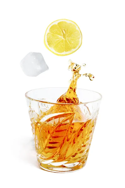 Ice cube with lemon drops from splashes into the glass with alco — Stock Photo, Image