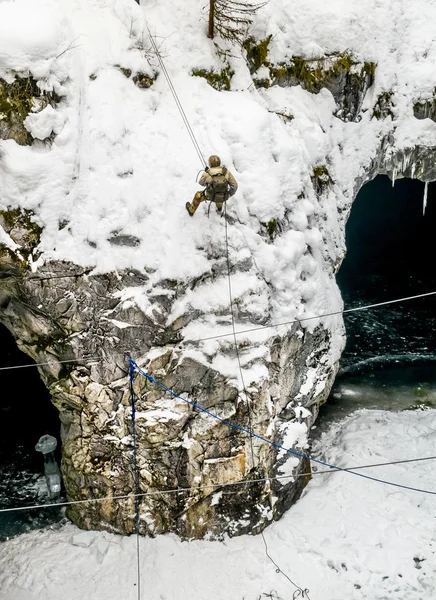 L'uomo con l'attrezzatura da alpinismo che scende su una corda per il — Foto Stock