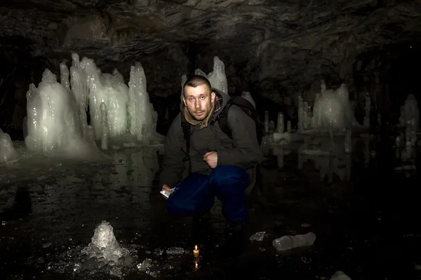 Uomo con una candela accesa siede in una grotta con blocchi di ghiaccio — Foto Stock