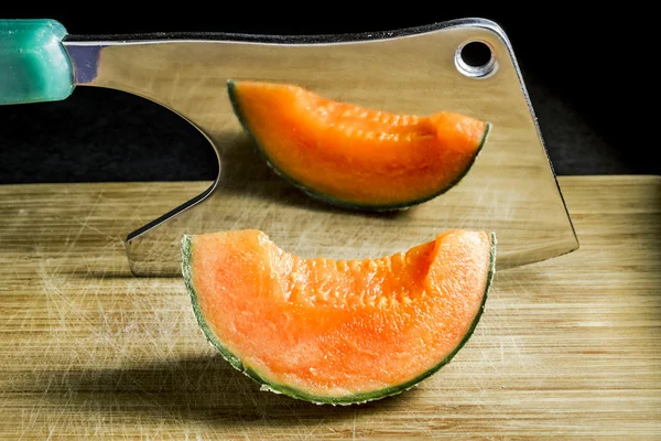 piece of succulent melon rests on the Board with an axe