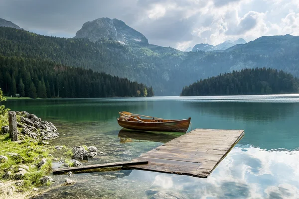 Boat on Black Lake in the national park Durmitor and mountains i — Stock Photo, Image