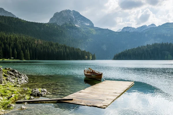 Boat on Black Lake in the national park Durmitor and mountains i — Stock Photo, Image