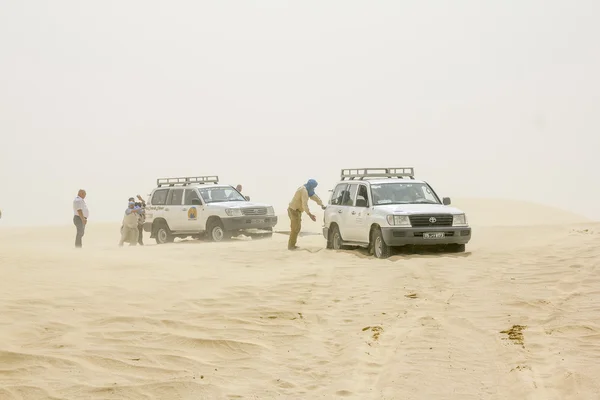The caravan of SUVs stuck in the Sahara desert in a sandstorm.Tu — Stock Photo, Image