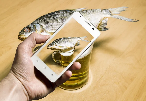 Vista da caneca com cerveja e peixe seco através da câmera de um — Fotografia de Stock