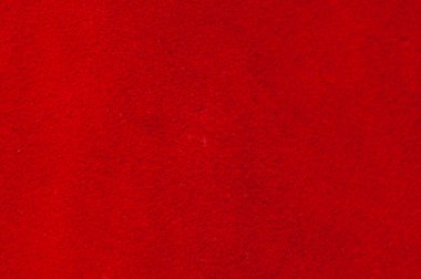 Kırmızı doku. Süet kumaşın kırmızı mat arka planı, yakın plan. Pürüzsüz deri kadife desenli. Keçeli kumaş makro
