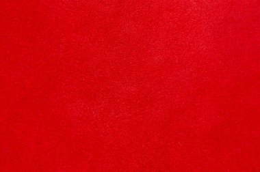 Kırmızı doku. Süet kumaşın kırmızı mat arka planı, yakın plan. Pürüzsüz deri kadife desenli. Keçeli kumaş makro