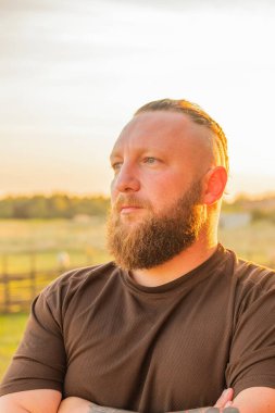 Hippi tarzı sakallı adam. Çekici adam, uzun saçlı, Avrupalı görünümlü, sakallı. Kahverengi tişörtlü adam.