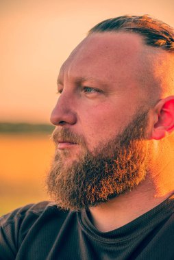 Hippi tarzı sakallı adam. Çekici adam, uzun saçlı, Avrupalı görünümlü, sakallı. Kahverengi tişörtlü adam.