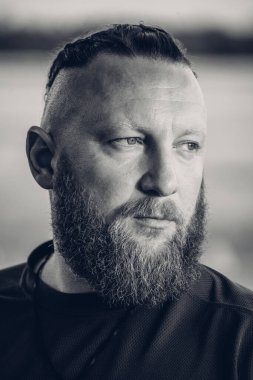 Hippi tarzı sakallı adam. Çekici adam, uzun saçlı, Avrupalı görünümlü, sakallı. Kahverengi tişörtlü adam.