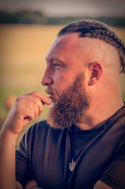 Hippi tarzı sakallı adam. Çekici adam, uzun saçlı, Avrupalı görünümlü, sakallı. Kahverengi tişörtlü adam.