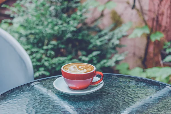 red coffee cup. Red Coffee cup in the garden. Coffee latte art in a red cup. Red cup of latte art. Morning coffee.