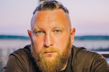 Hippi tarzı sakallı adam. Çekici adam, uzun saçlı, Avrupalı görünümlü, sakallı. Kahverengi tişörtlü adam.