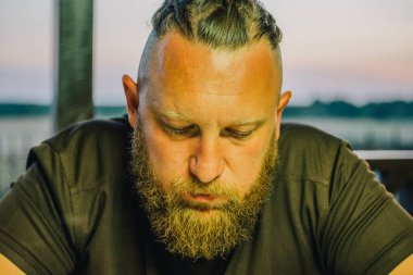 Hippi tarzı sakallı adam. Çekici adam, uzun saçlı, Avrupalı görünümlü, sakallı. Kahverengi tişörtlü adam.