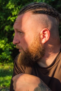 Hippi tarzı sakallı adam. Çekici adam, uzun saçlı, Avrupalı görünümlü, sakallı. Kahverengi tişörtlü adam. Ormandaki adam.