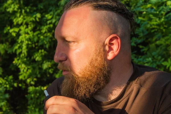 Hippi tarzı sakallı adam. Çekici adam, uzun saçlı, Avrupalı görünümlü, sakallı. Kahverengi tişörtlü adam. Ormandaki adam.