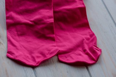 Ahşap arka planda pembe tayt. Kadın giysisi olarak pembe taytlar. Kıyafet, kumaş.