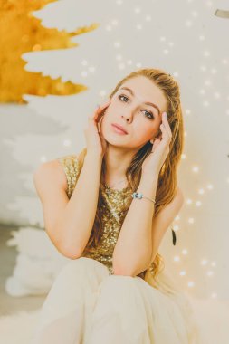 Noel, kış tatili konsepti. Noel için dekore edilmiş lüks dairelerde poz veren gece kıyafetli güzel bir kadın. Güzellik, moda. Noel için parlak elbiseli bir kız..