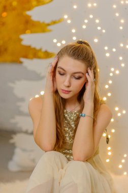 Noel, kış tatili konsepti. Noel için dekore edilmiş lüks dairelerde poz veren gece kıyafetli güzel bir kadın. Güzellik, moda. Noel için parlak elbiseli bir kız..