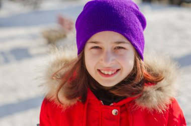 Güzel, sıcak kırmızı kıyafetli küçük kız karda dışarıda oynuyor. Kışın sokakta kırmızı ceketli bir kız. Kışın 9-10 yaşlarında bir okul kızı..