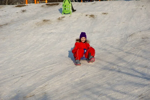 小女孩穿着漂亮的温暖的红色衣服在外面雪地里玩耍 冬天穿红色夹克的女孩在街上 一个9岁或10岁的学龄女孩 — 图库照片