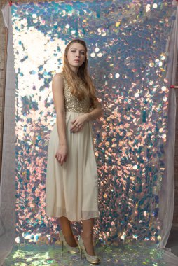 Parlak arka planda poz veren gece elbisesi içindeki muhteşem genç bayan. Parlak bir arka planda gece elbisesi giymiş bir kız.