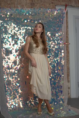 Parlak arka planda poz veren gece elbisesi içindeki muhteşem genç bayan. Parlak bir arka planda gece elbisesi giymiş bir kız.